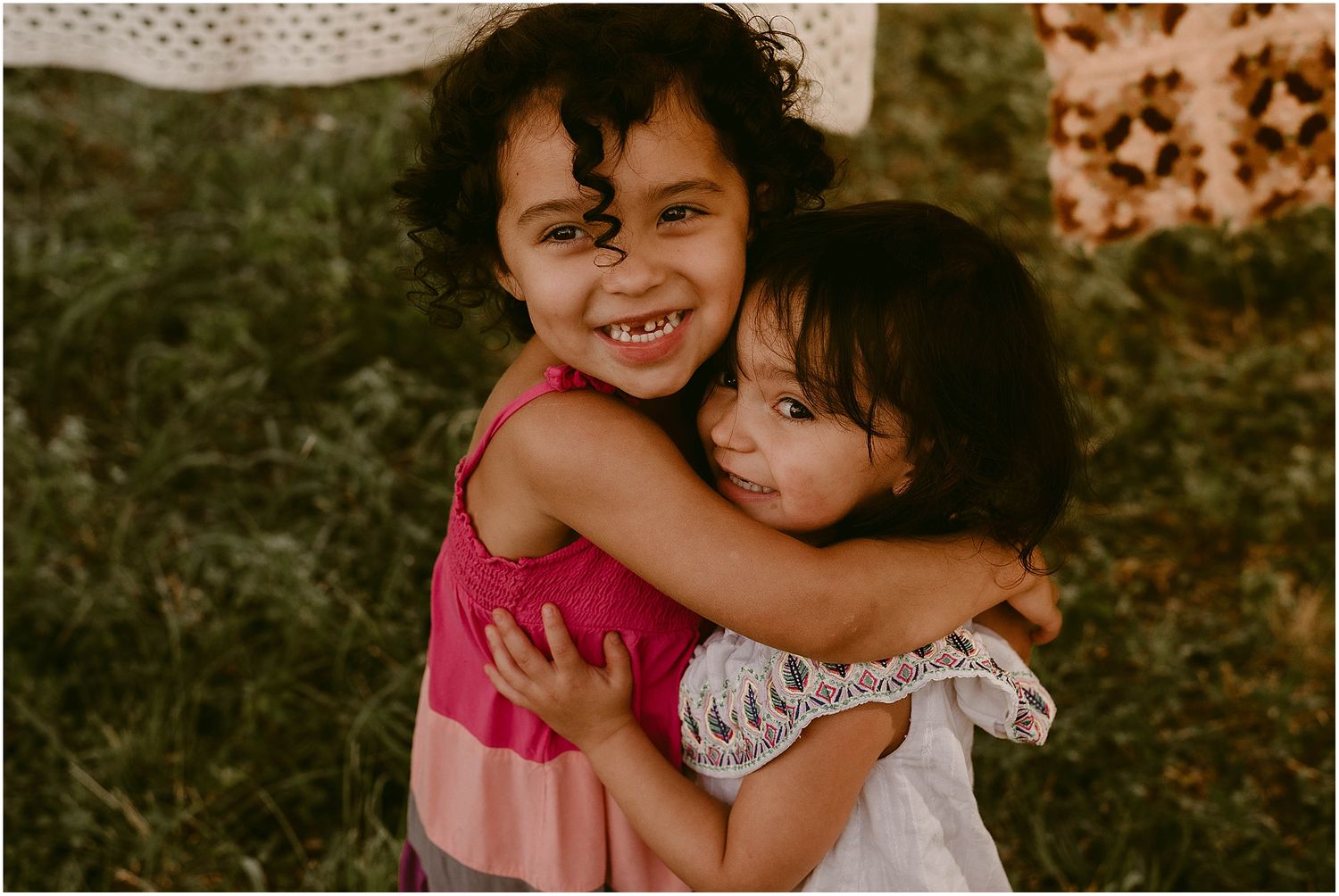 Close-up of children hugging and laughing with vintage-style backdrop.