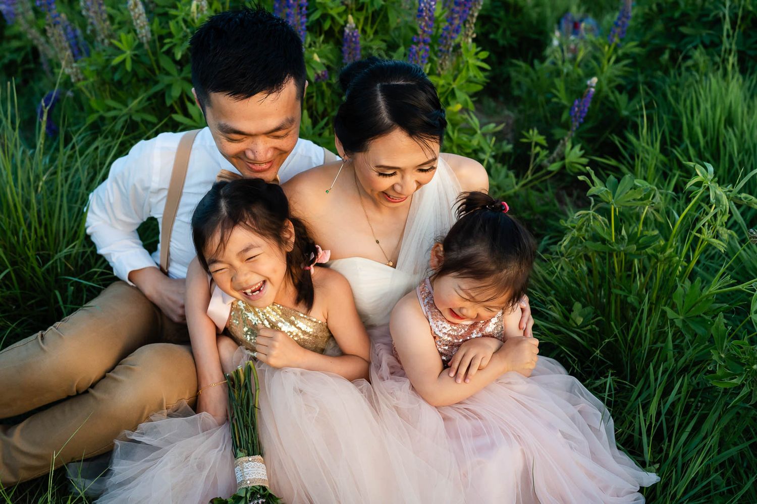Seattle family sitting in a field of lupines and laughing.