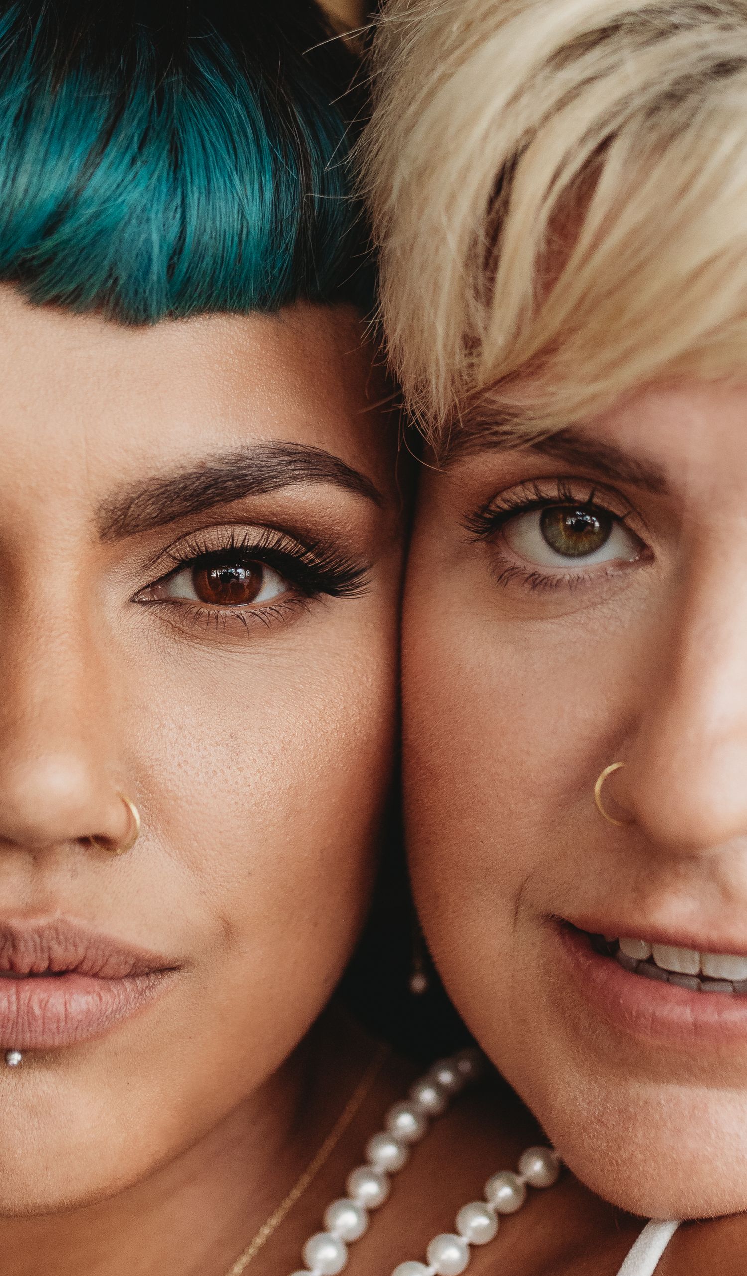 A close-up portrait showing contrasting hairstyles with teal and platinum blonde colors.