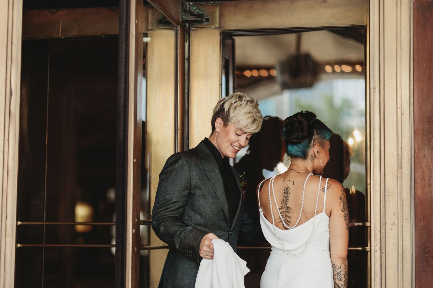 A couple shares an intimate moment in formal attire near an elegant doorway.