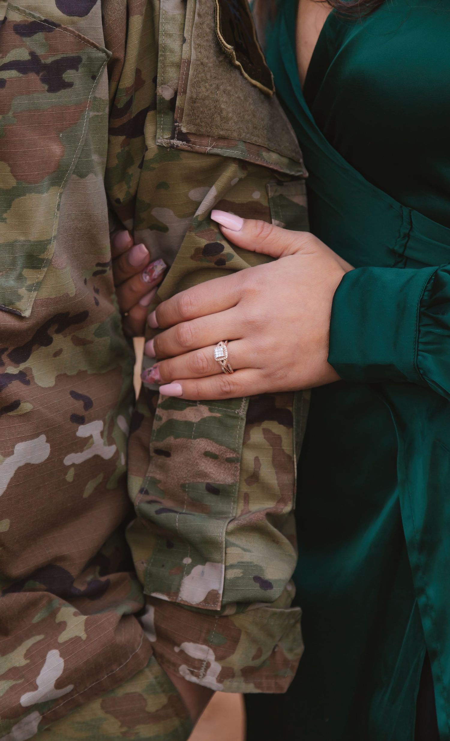 engagement ring close up, womans hand is linked into mans arm
