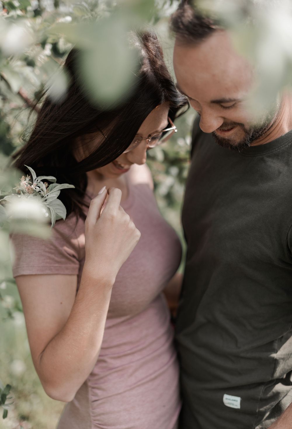 Intimate spring portrait among blooming trees with soft bokeh effect.