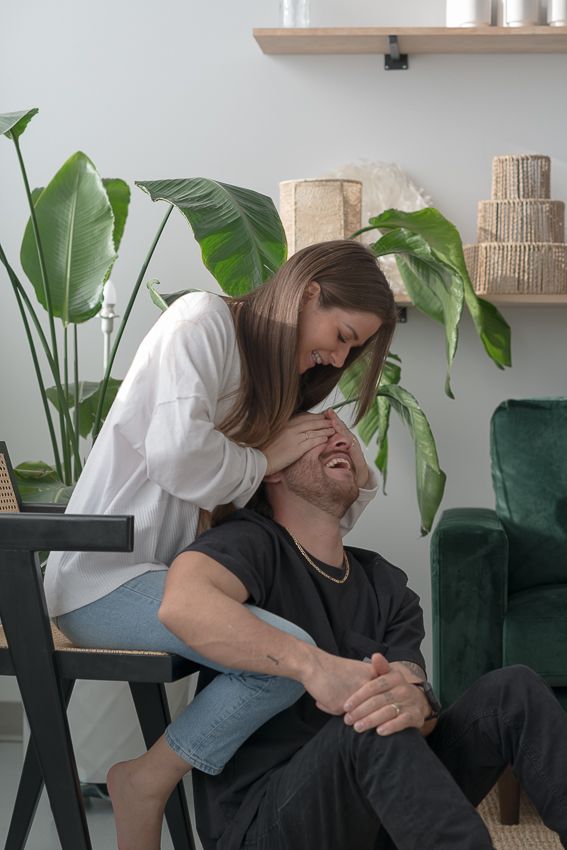 An intimate moment between a couple on a dark couch with houseplants in the background.