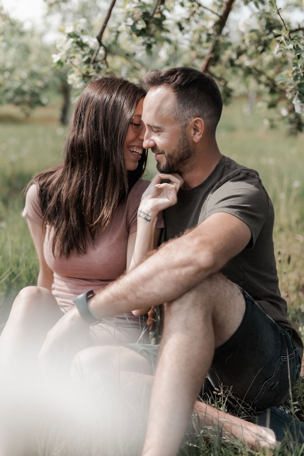 Romantic couple sharing intimate moments in a spring garden setting with blooming trees in the background.