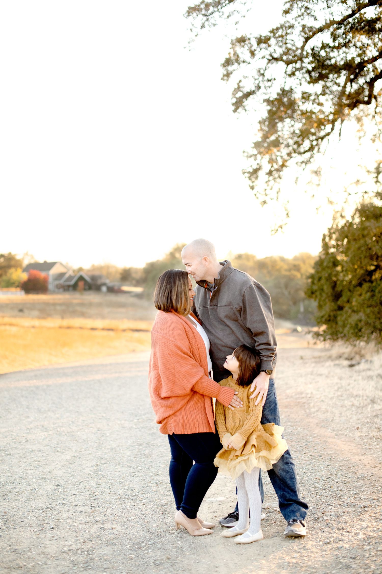 Family members share a sweet moment together on a dirt path during golden hour.