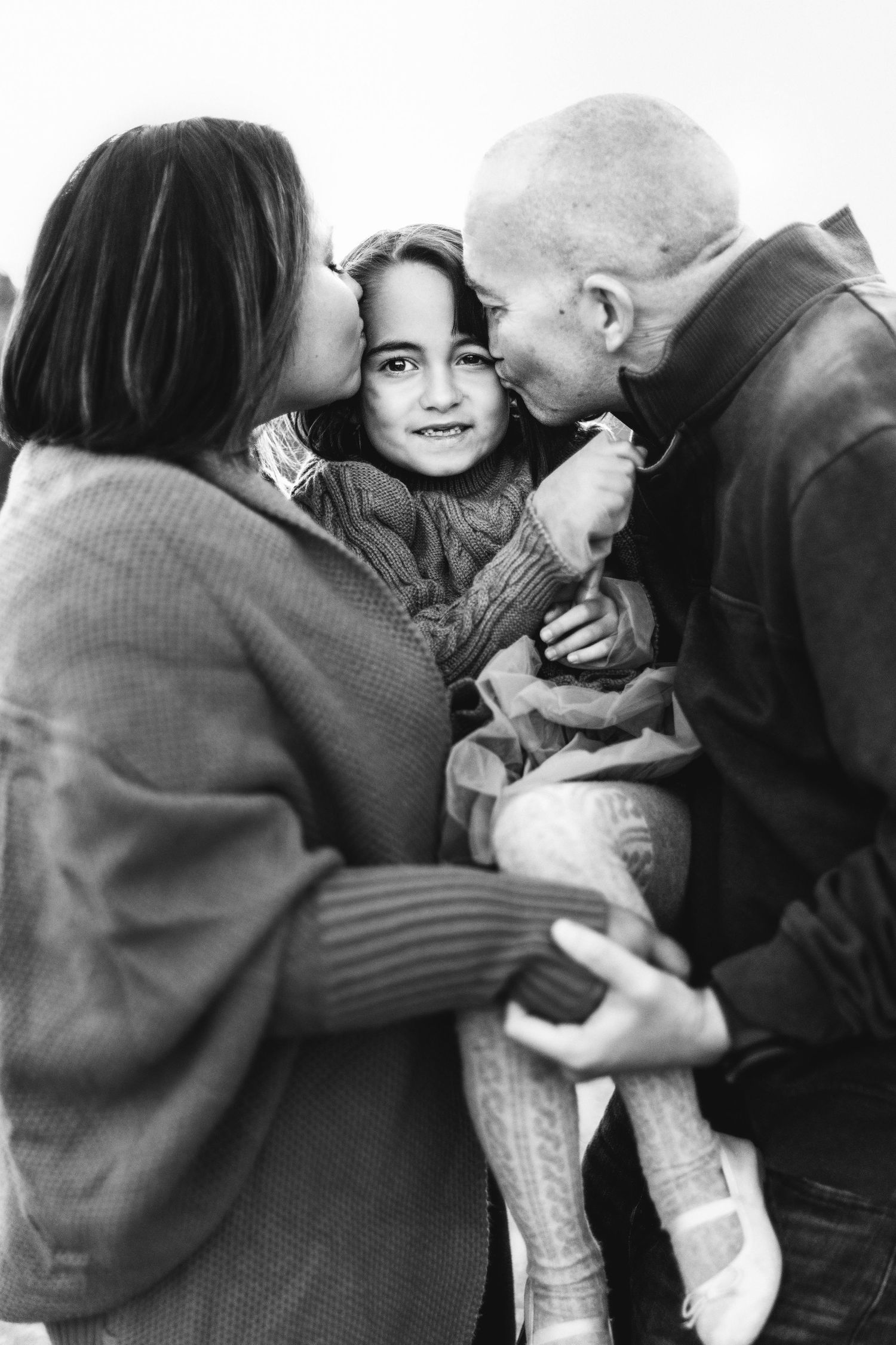 Intimate black and white portrait of family embracing and sharing affectionate moment.