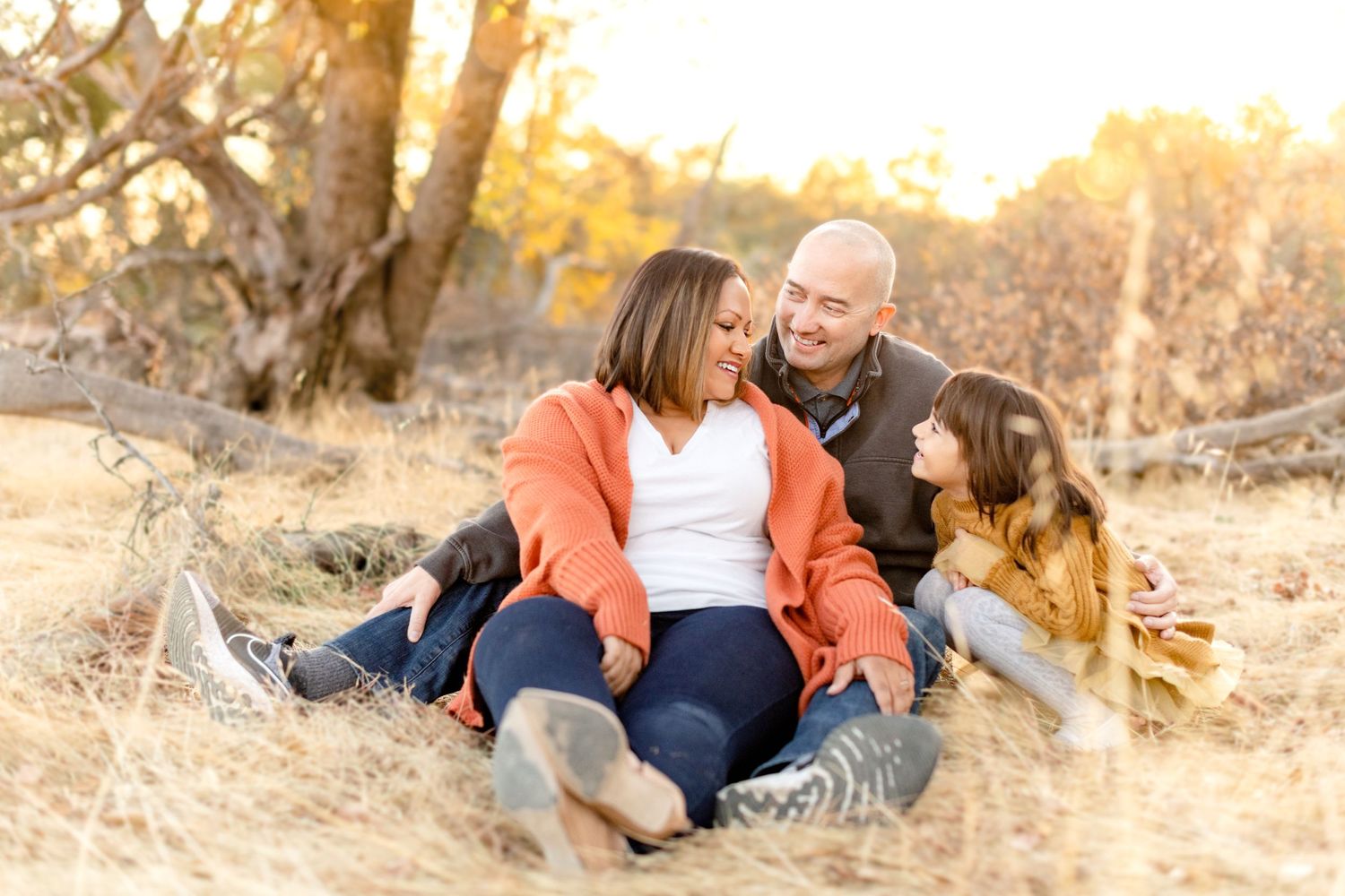 A candid family photoshoot outdoors during golden hour showing joyful interactions on a nature trail.