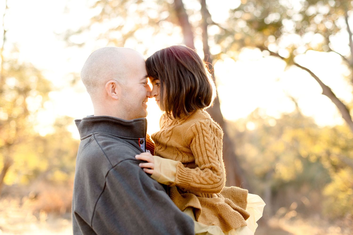 Two people share an intimate moment during a sunset photo session outdoors.