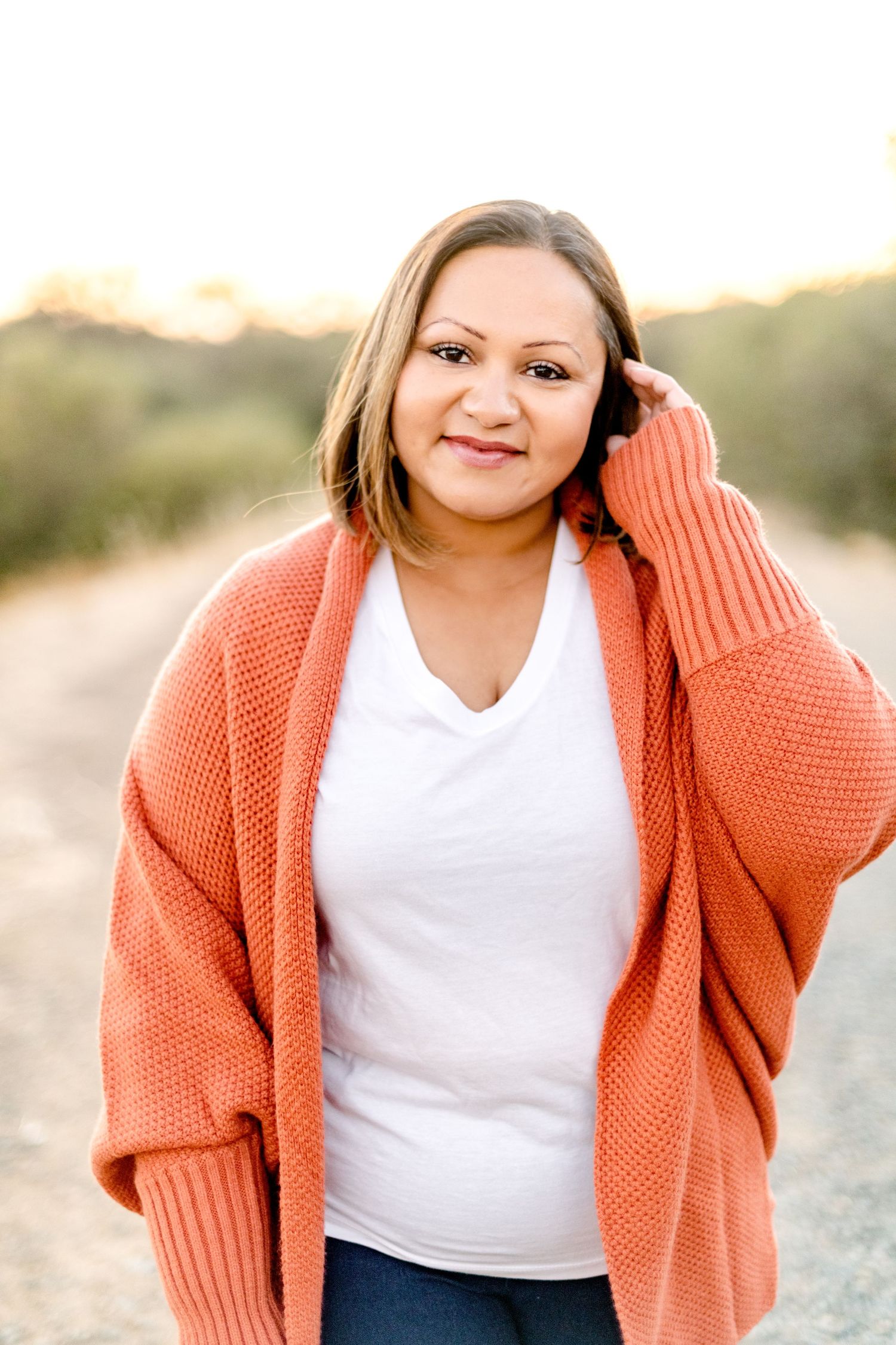 Portrait series showing someone in a coral sweater and white top smiling outdoors.