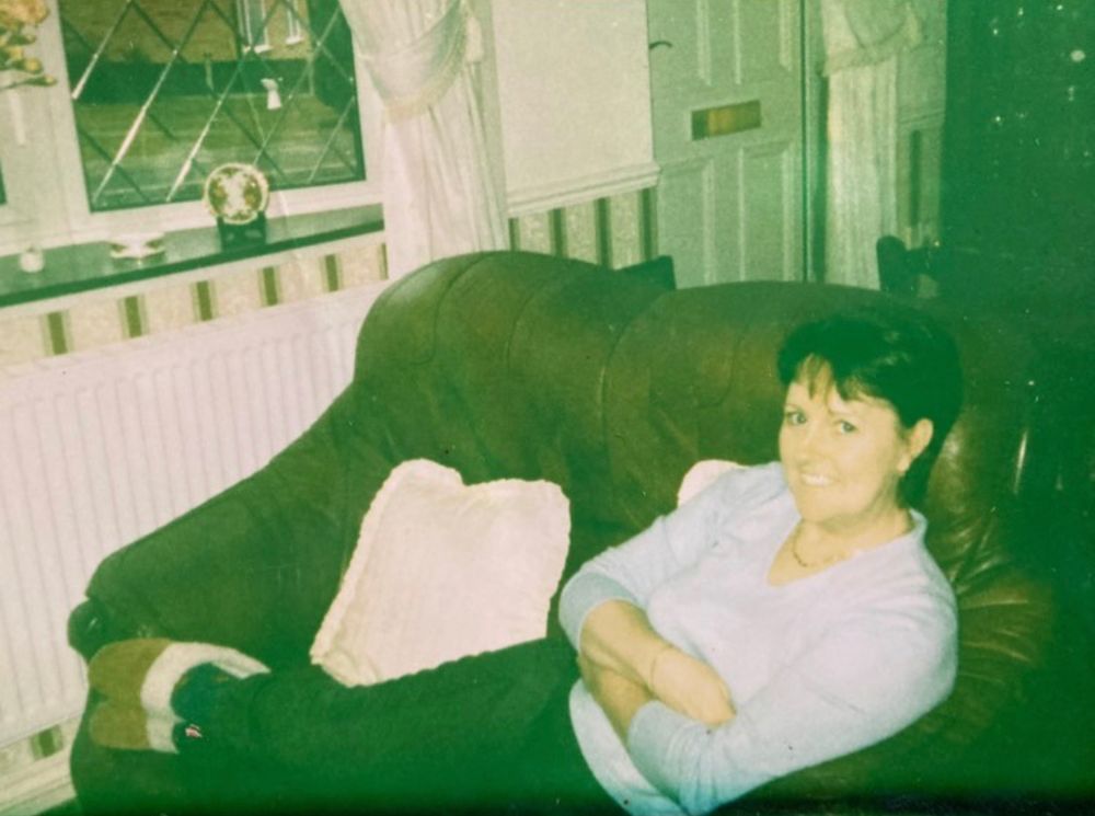 Vintage photo with green tint shows person resting on couch in residential room.