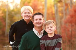 Autumn family portrait with fall foliage in background.
