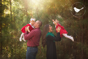 Family enjoying playful moment in forest with golden sunlight streaming through trees.