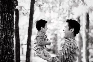 Black and white portrait capturing joyful moment between parent and child outdoors.