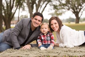 Family relaxing together on sand with natural outdoor setting.