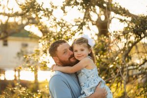Tender moment between parent and child captured during sunset in a garden setting.