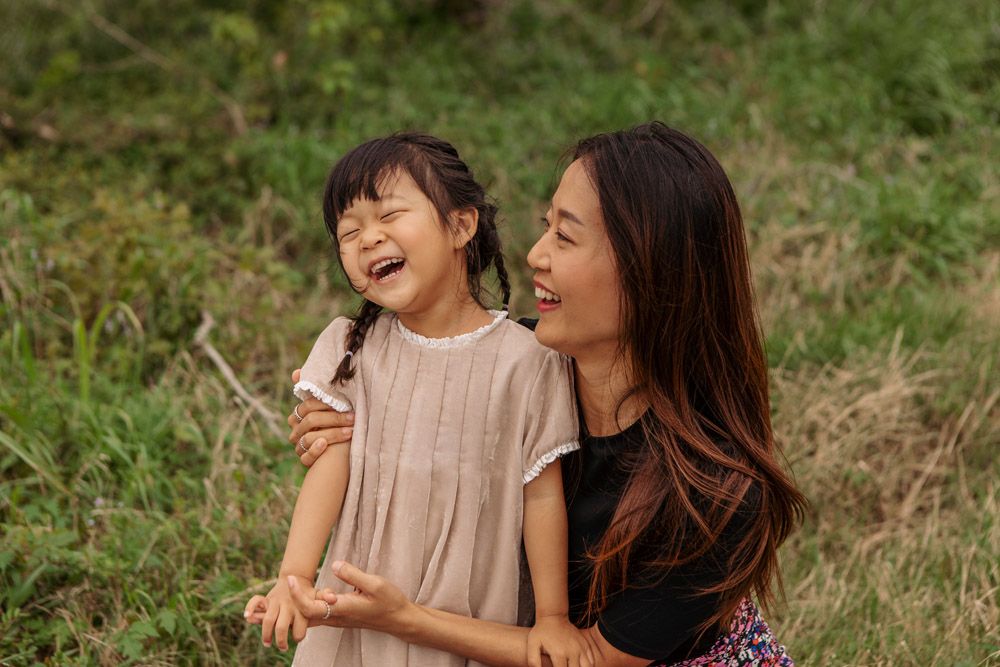 Candid moment of joy and laughter between parent and child in outdoor natural setting.
