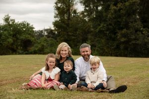A family group relaxes together on grass during an outdoor photo session.