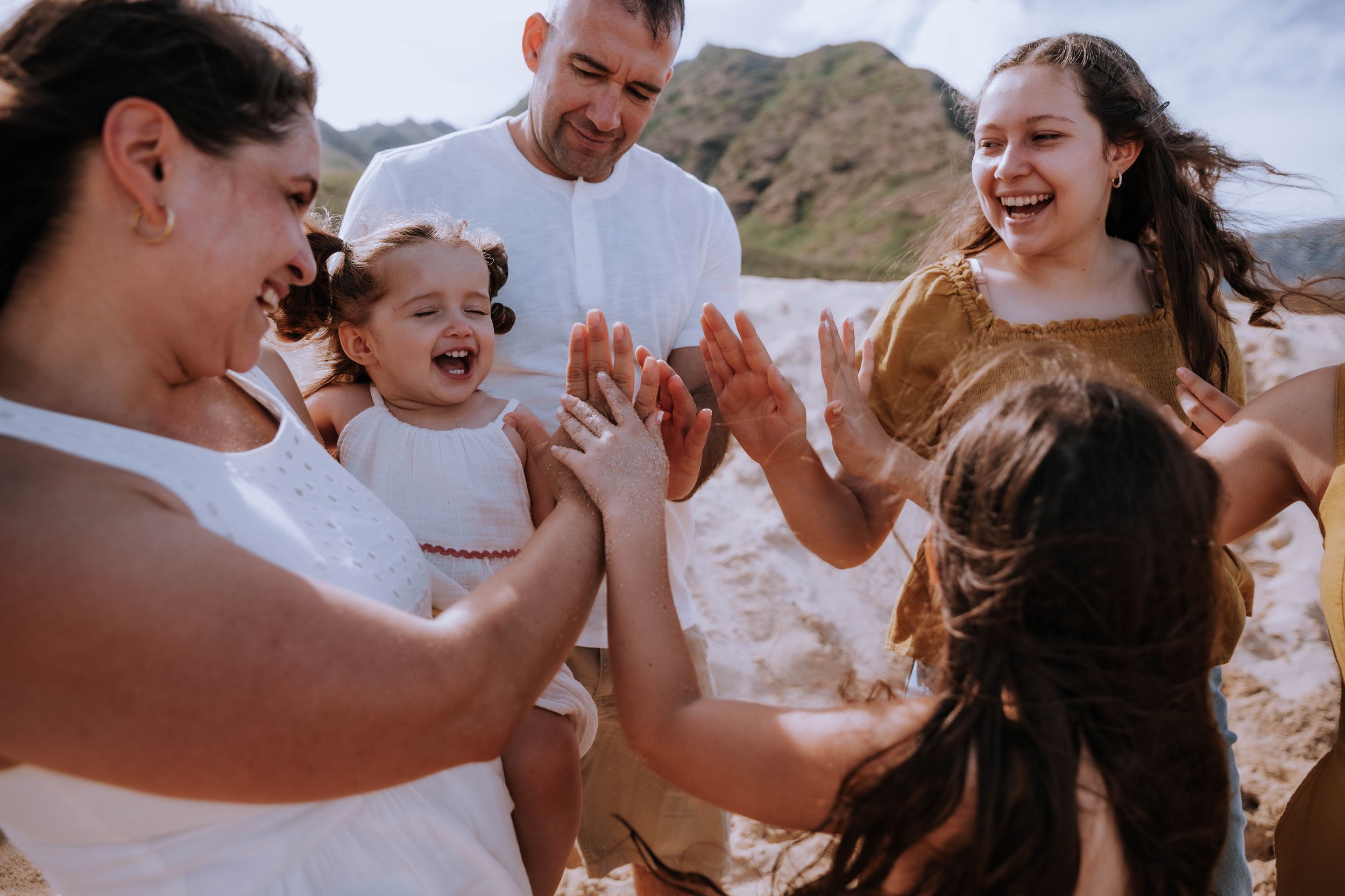 Joyful moments shared between people on beach with mountains in background.