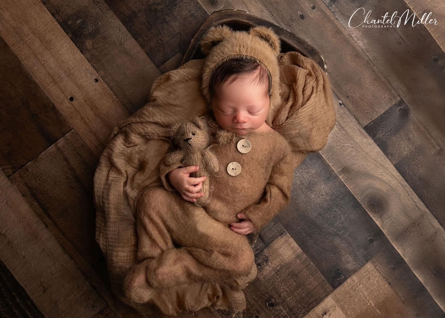 Above view of a cozy newborn photography setup with brown fabric and wooden plank background.