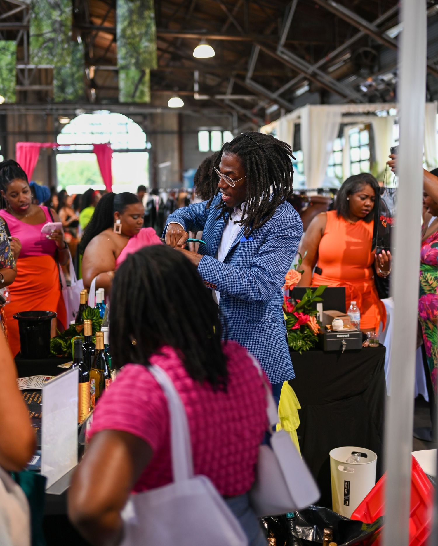 People interacting at a lively indoor market with vendors and shoppers.