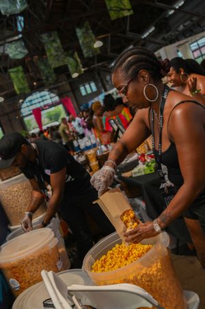 Person scooping food from large containers at an indoor market or festival event.
