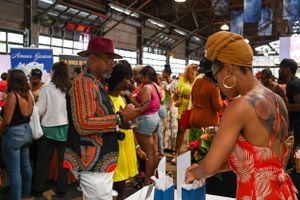 Shoppers browsing vendor stalls at a busy indoor market event.