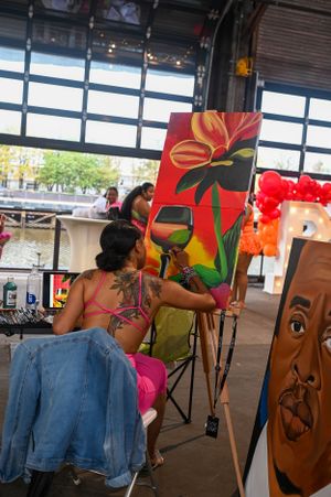An artist painting a vibrant red floral artwork at an outdoor market event.