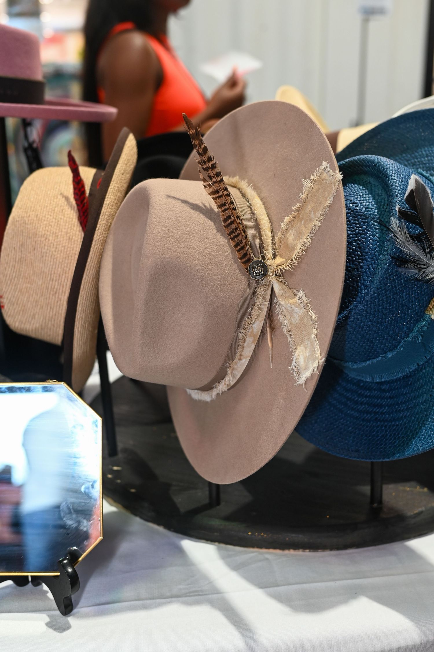 A display of western-style hats with feather decorations on a retail stand.