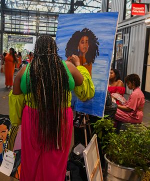 A colorful art display featuring paintings at an indoor market venue.