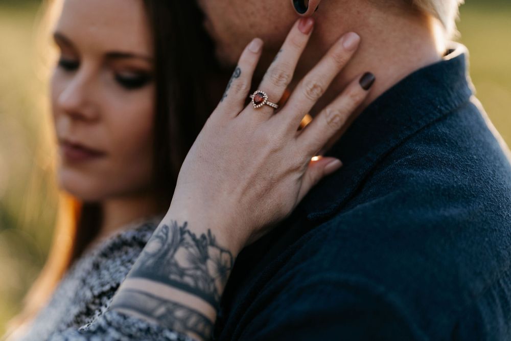 Close up of engagement ring and tattoo sleeve as couple embraces.