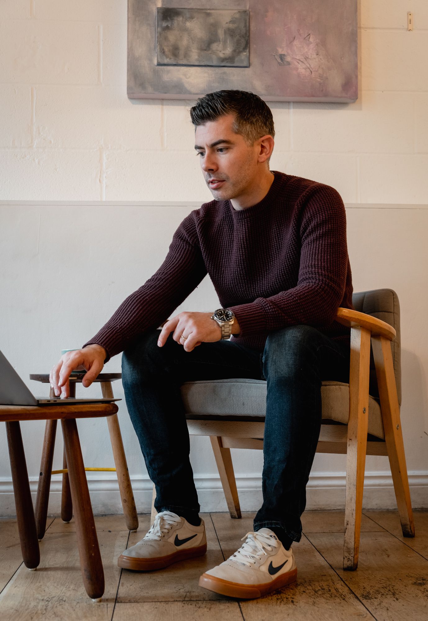 founder man sitting in chair wearing burgundy jumper and watch