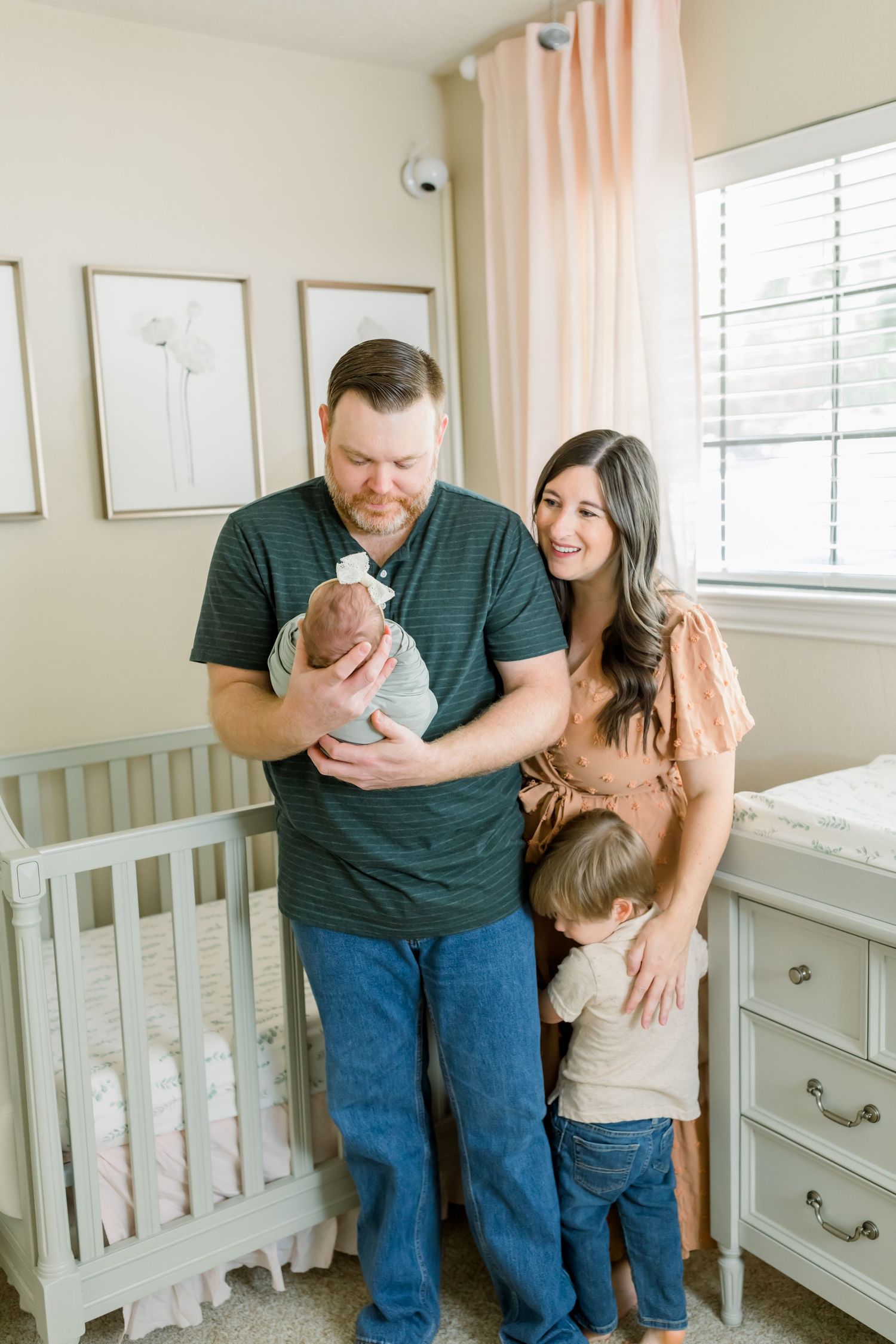 A family shares a sweet moment together in their nursery decorated with minimalist wall art.