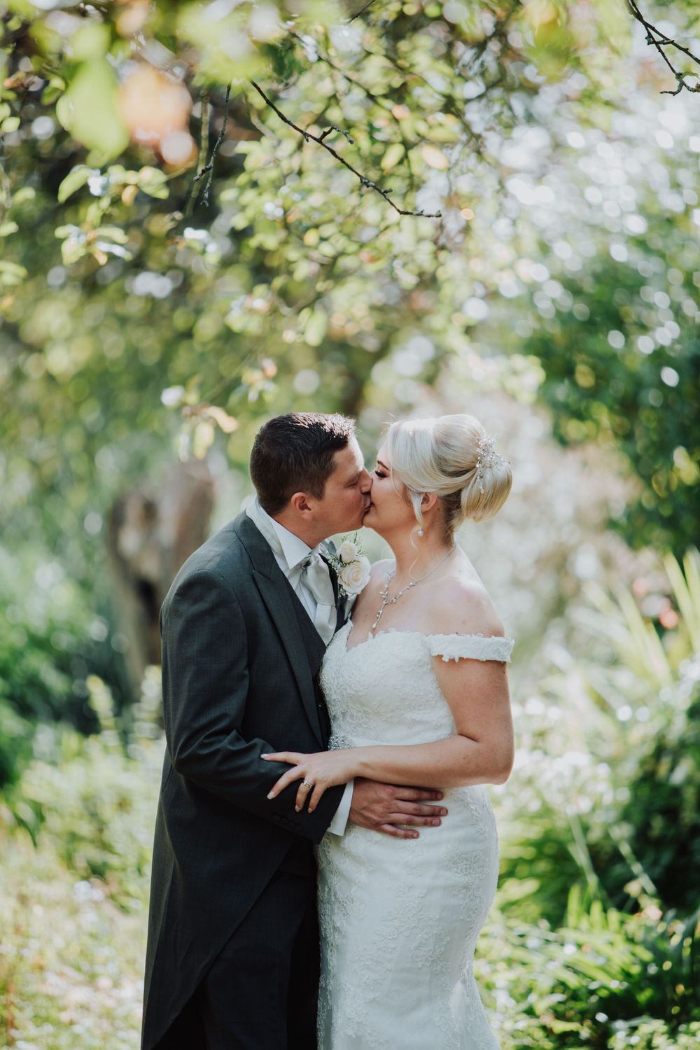 Romantic garden wedding portrait with couple sharing intimate moment under blooming trees.