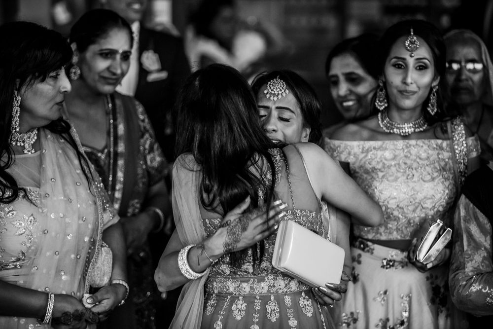 Black and white photo of wedding guests dancing and celebrating in traditional Indian attire.