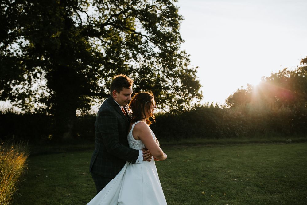 A couple dances in an outdoor setting during sunset on their wedding day.