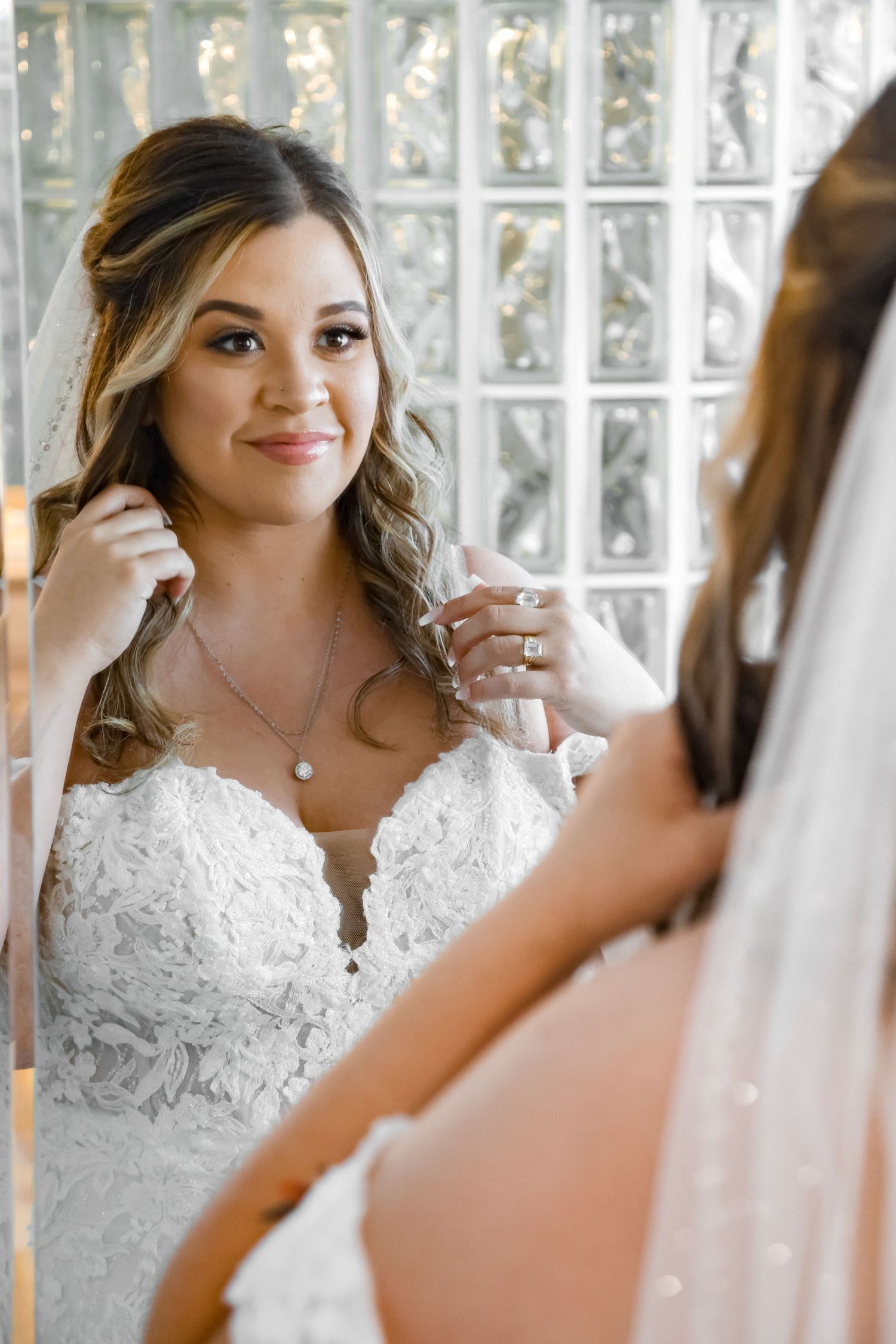 A close-up view of a lace wedding dress with glass block window background.