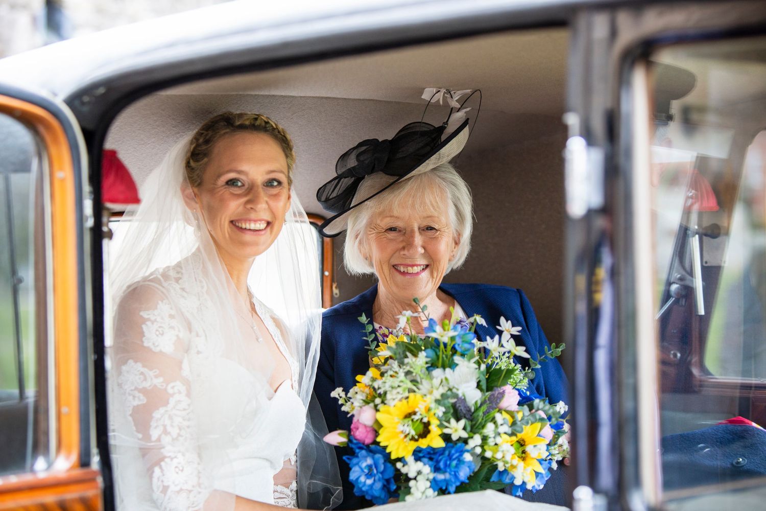 Classic vintage car interior decorated with bright yellow and blue wedding flowers.