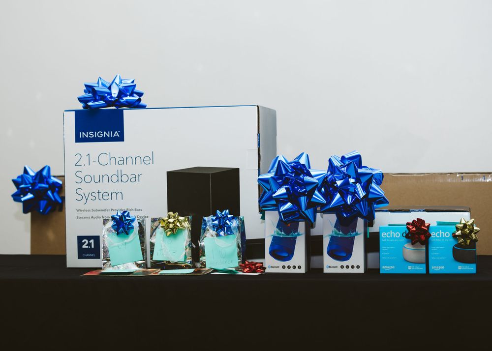 Product display featuring blue-decorated gift boxes and sound system equipment arranged on a black table.