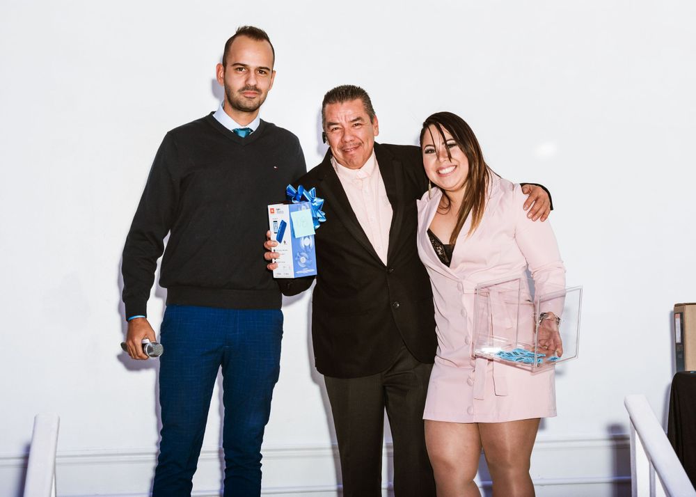 Group photo of three people holding promotional products at corporate event.