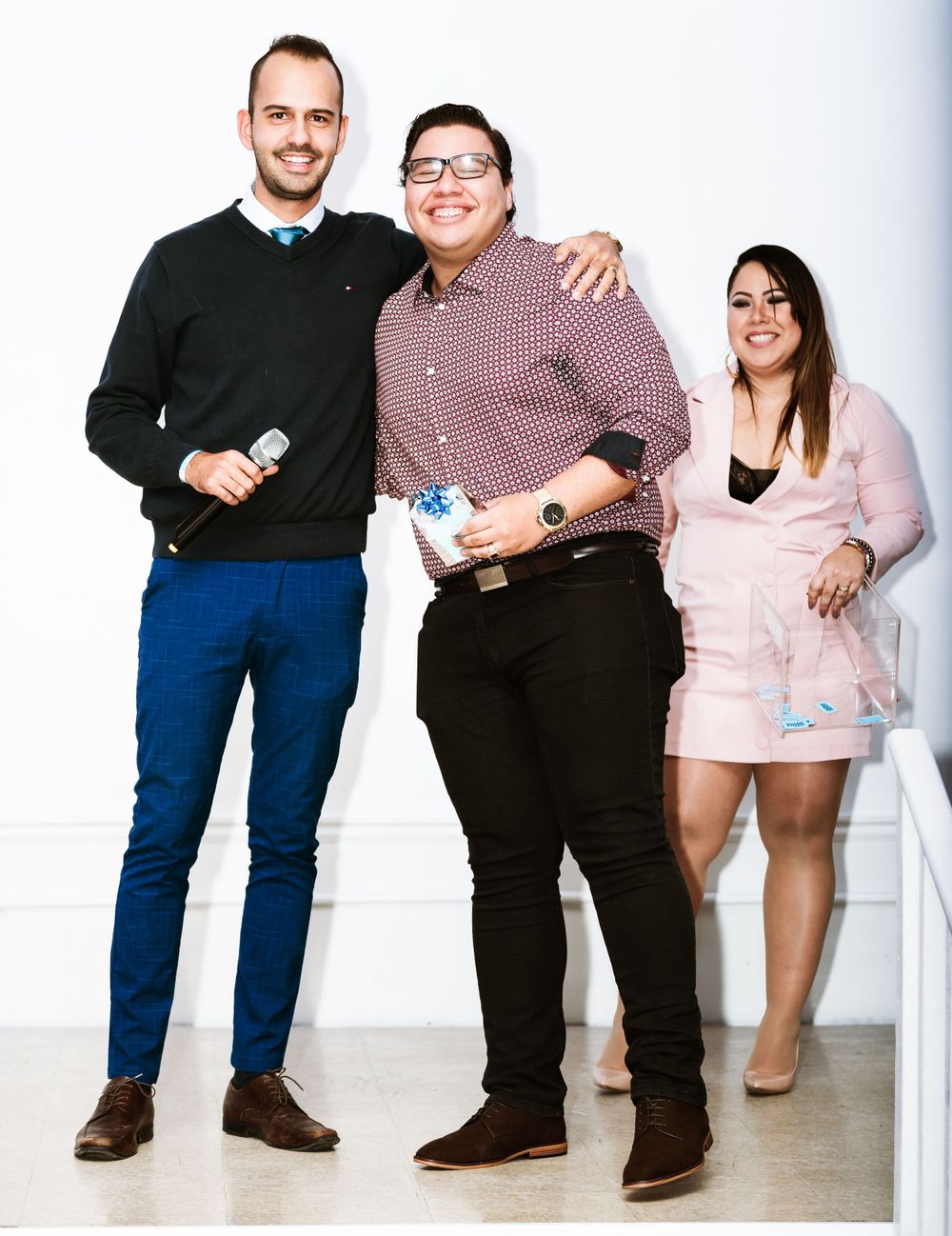 Three people standing together at promotional event with branded merchandise.
