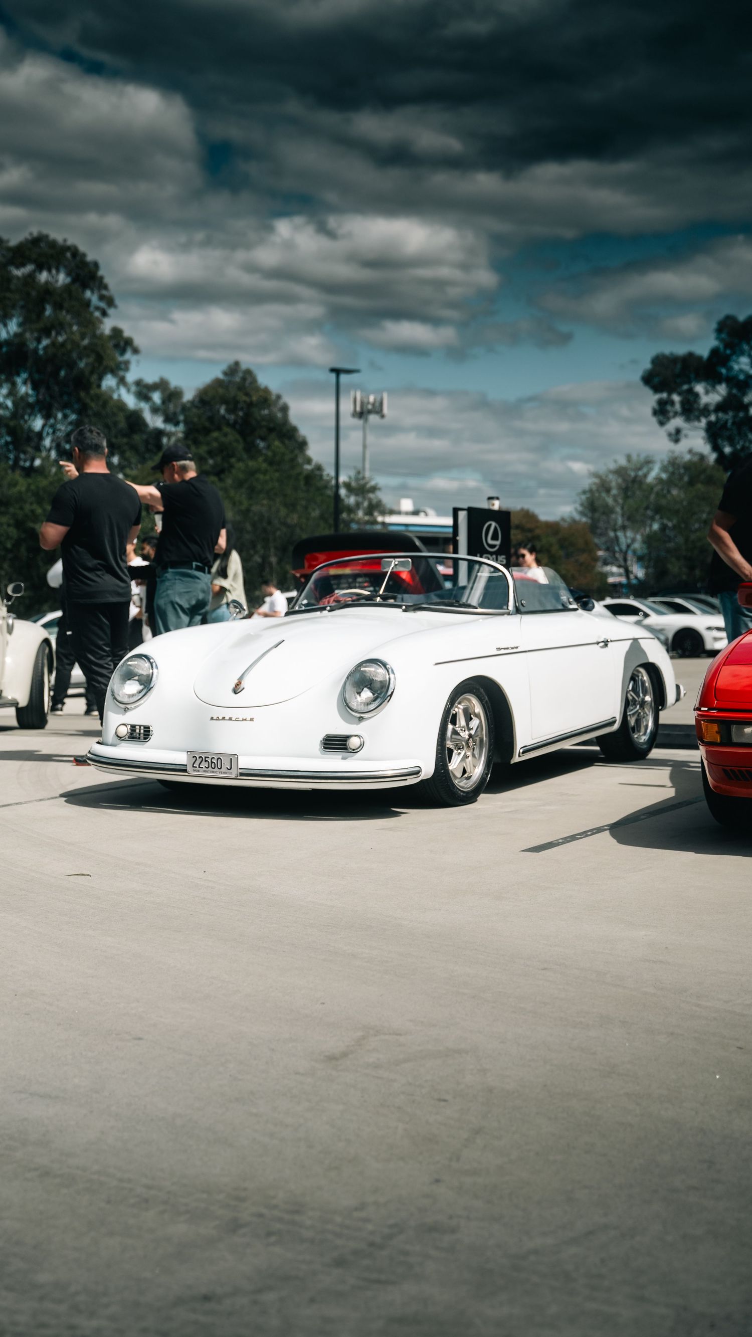 Classic white Porsche 356 Speedster convertible displayed at an outdoor car show under cloudy skies.
