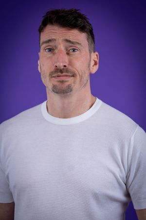 Comedian Alex Howard against a purple background shot in studio in Amy Davies Photography studio in Hove