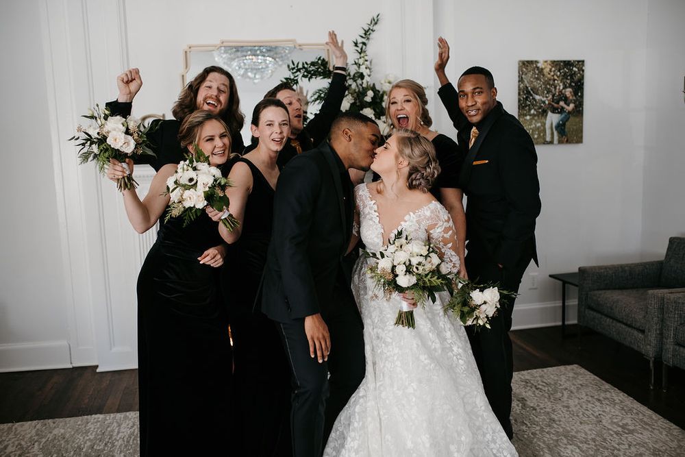 Joyful wedding party celebrating with bride and groom in a bright elegant room.