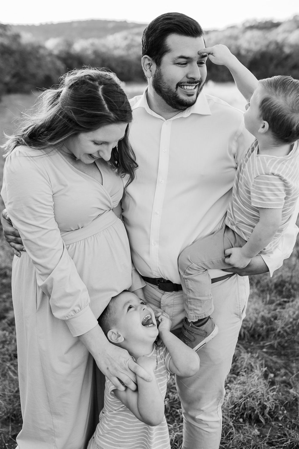 Black and white family portrait capturing candid laughter and joy outdoors.