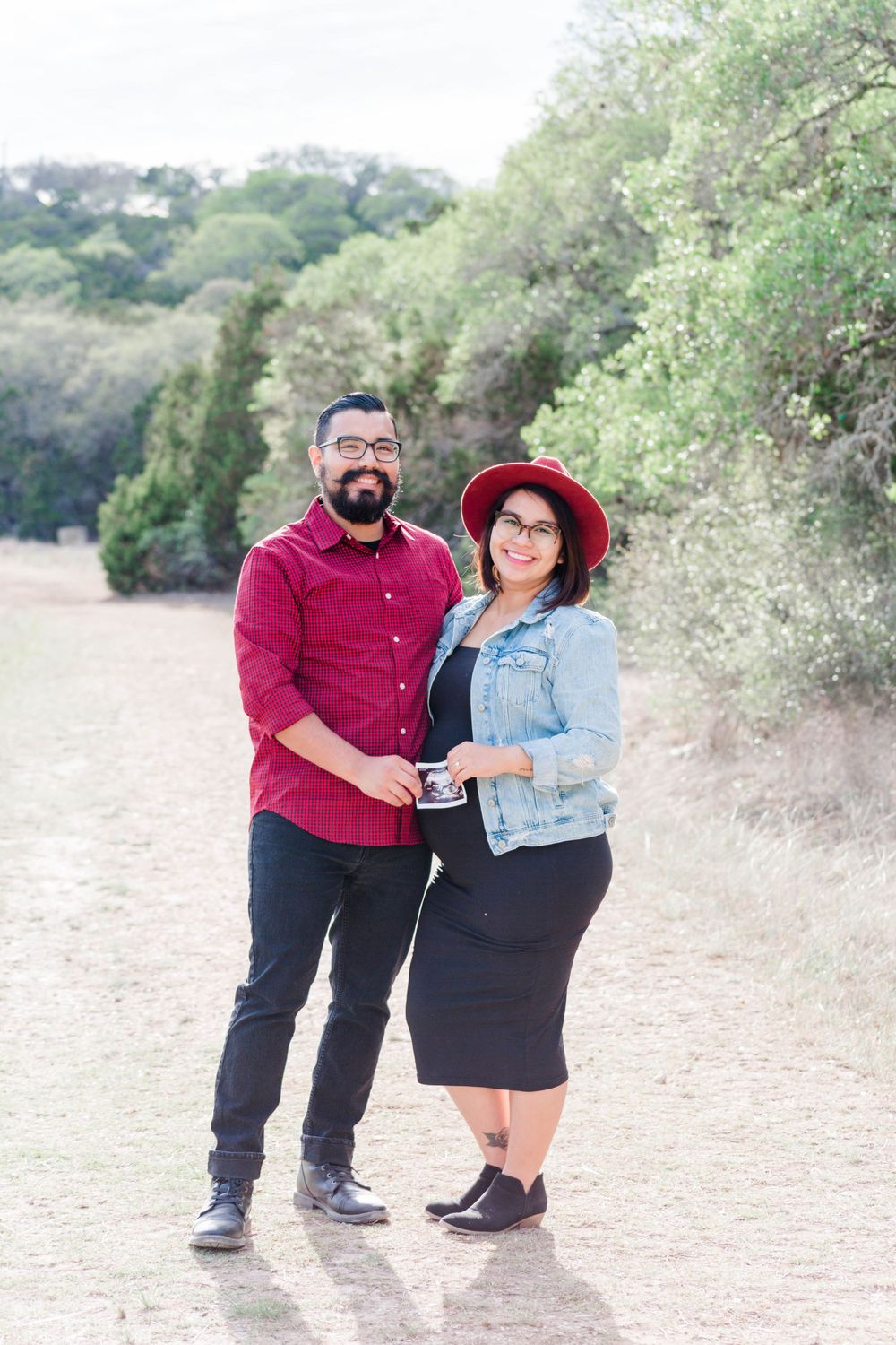 A couple poses together on a nature trail wearing coordinated red and denim outfits.