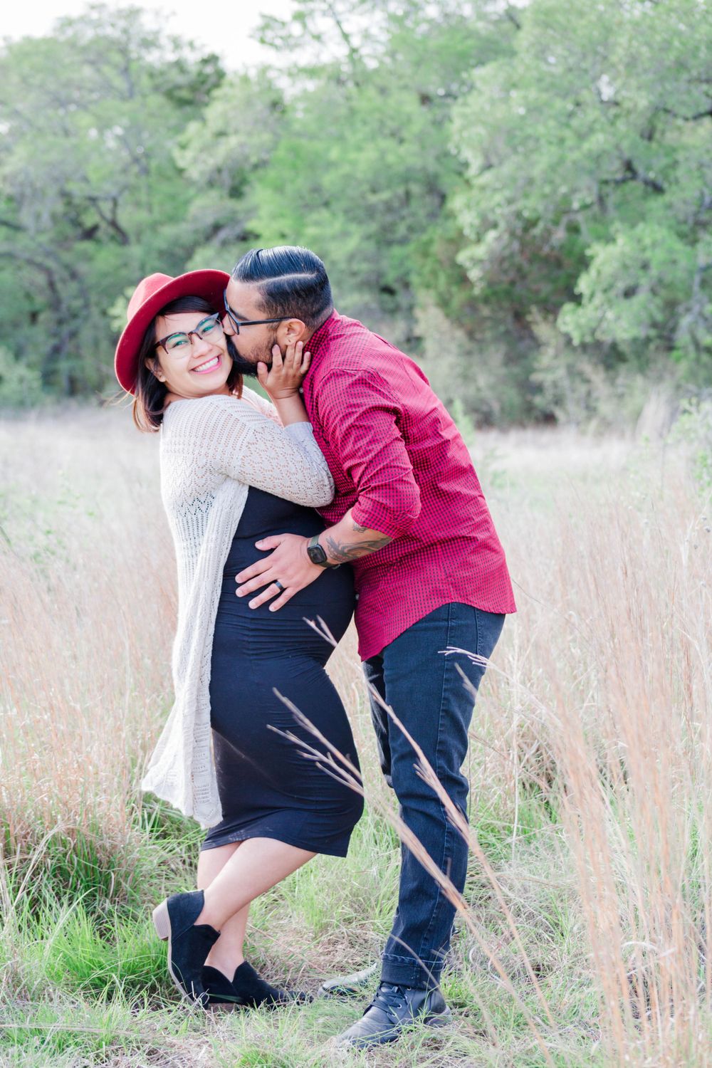A romantic moment shared between a couple in casual attire standing in a field of tall grass.