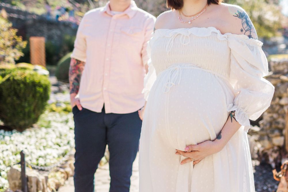 Maternity photo showing couple in coordinating pink and white outfits.