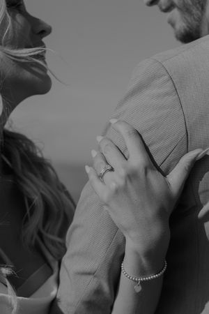 Close-up of hands embracing showing engagement ring and bracelet details.