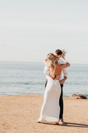 Couple sharing intimate dance on cliff edge with ocean backdrop.