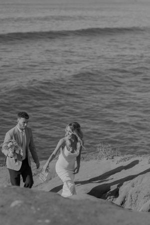Black and white photo of couple walking along coastal cliff path.